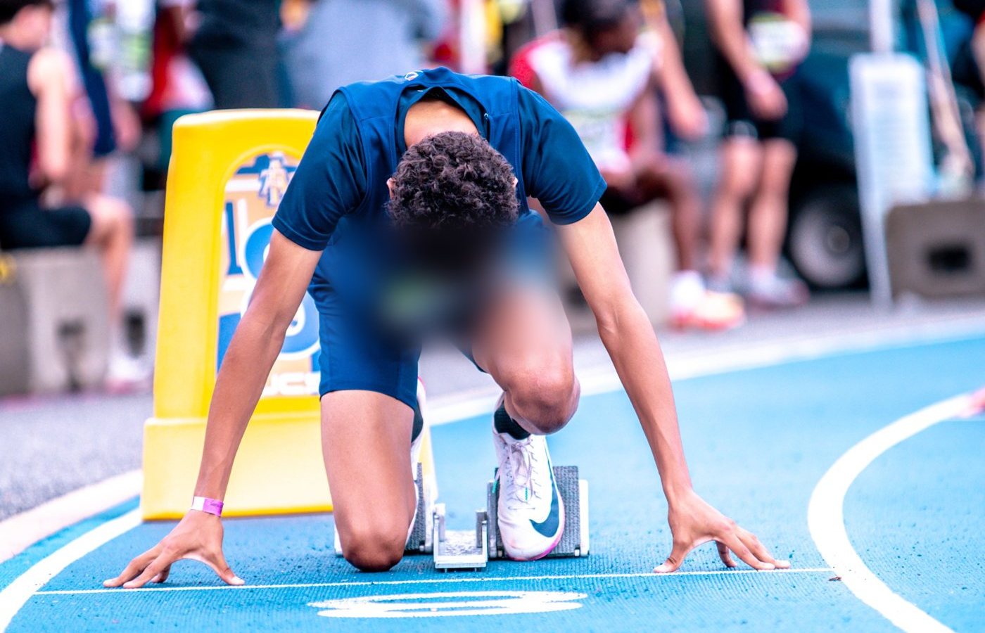 A young sprinter kneels in the starting blocks before a race